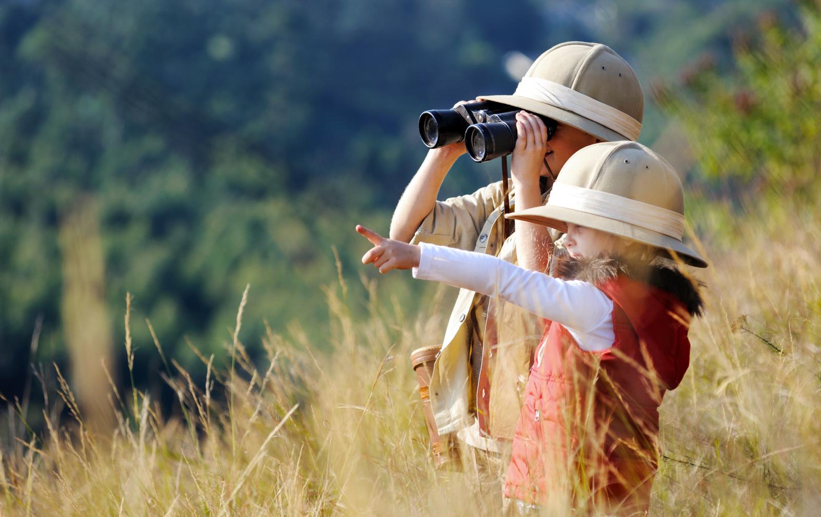 Two young kids on a safari using binoculars
