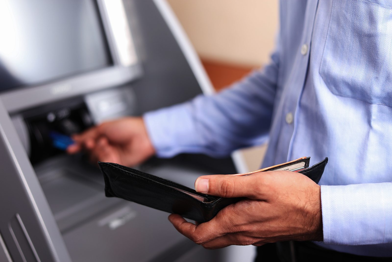 a man takes cash out of a checking account at an ATM