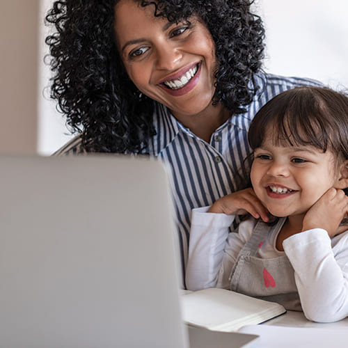 mother and young daughter looking at laptop