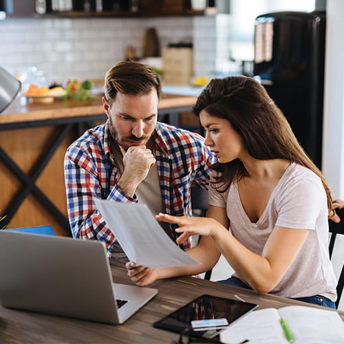 young couple looking over paperwork with laptop